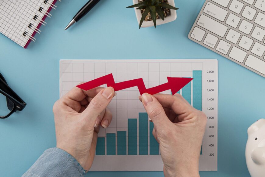 top-view-business-items-with-growth-chart-hands-holding-arrow-scaled