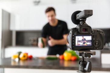 Close up of a video camera filming young smiling male blogger