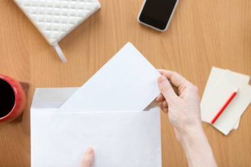 Female hands holding an envelope with a sheet over the office de