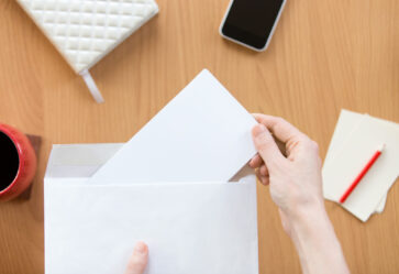Female hands holding an envelope with a sheet over the office de